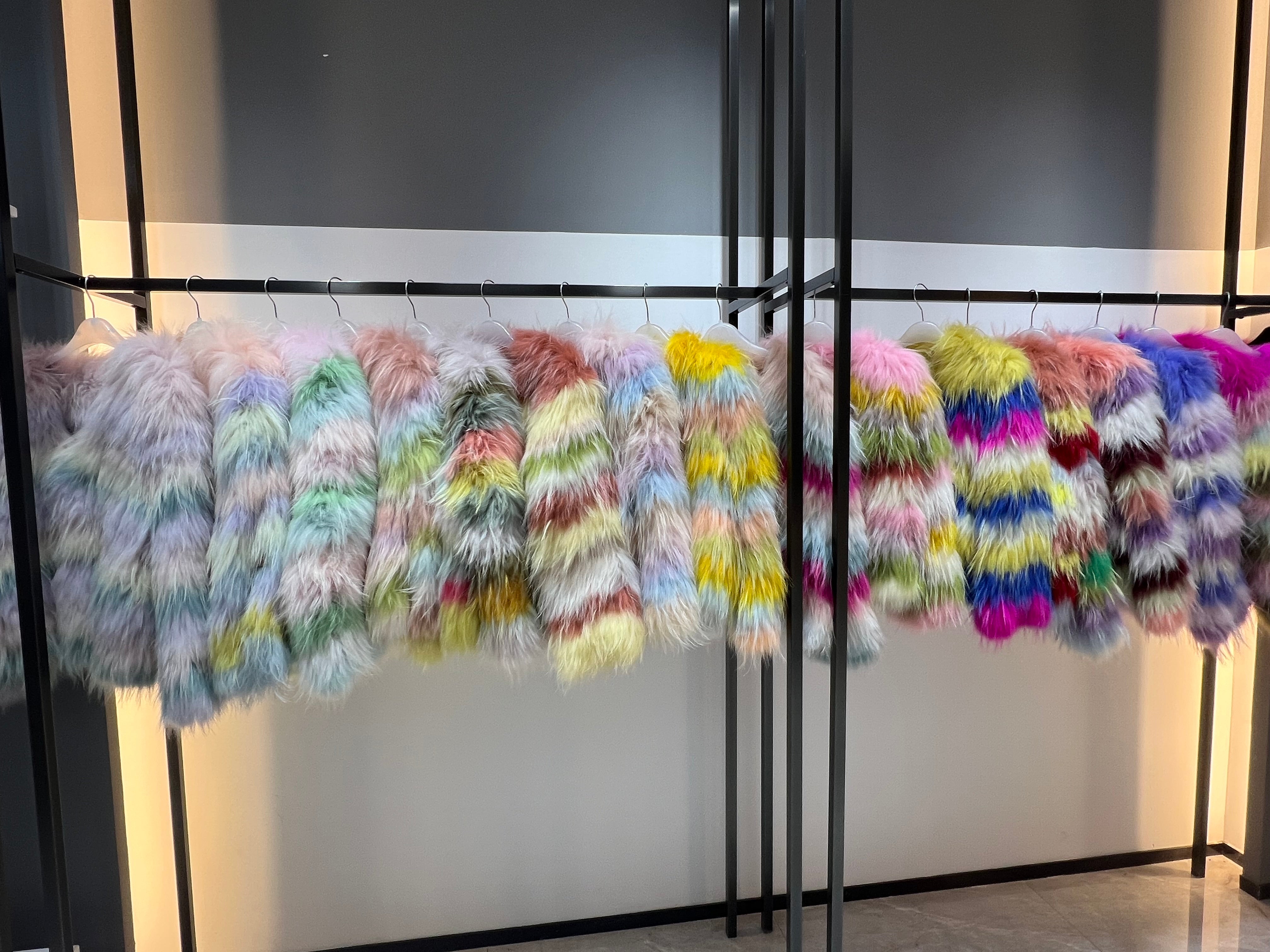 Colorful luxury fur coats display featuring vibrant pastels, neons, and jewel tones