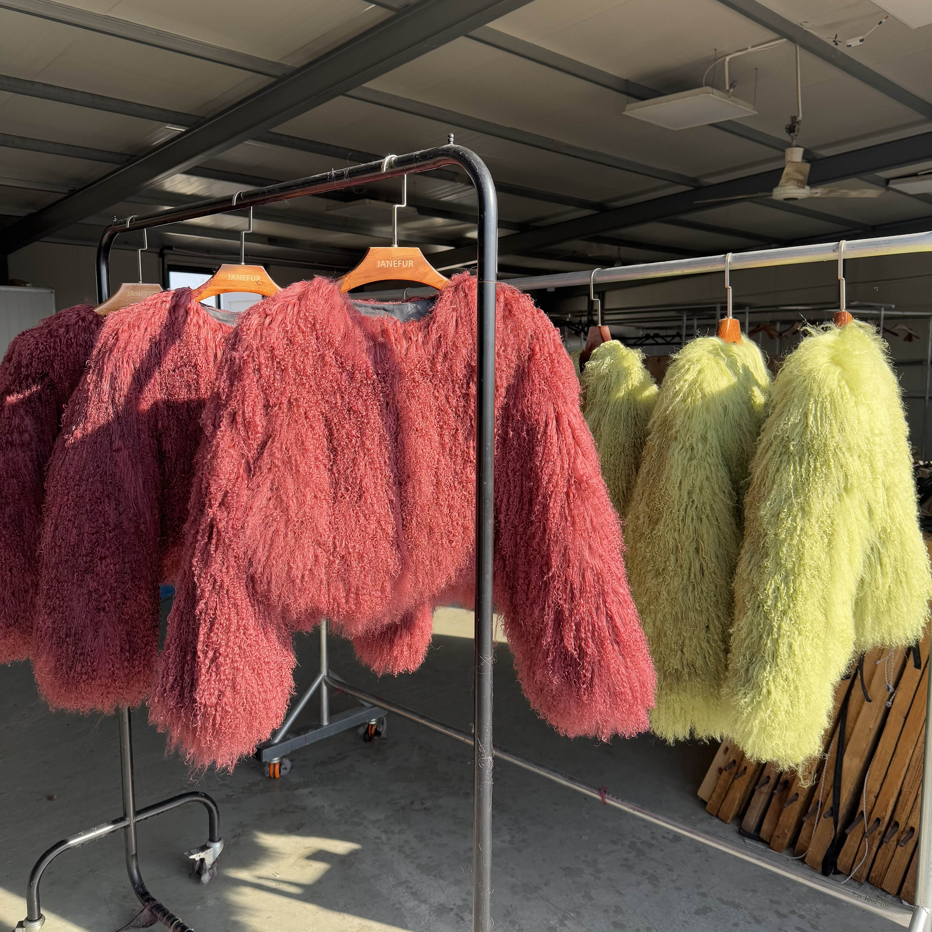 Colorful Tan sheep fur jackets in pink and yellow displayed on hangers