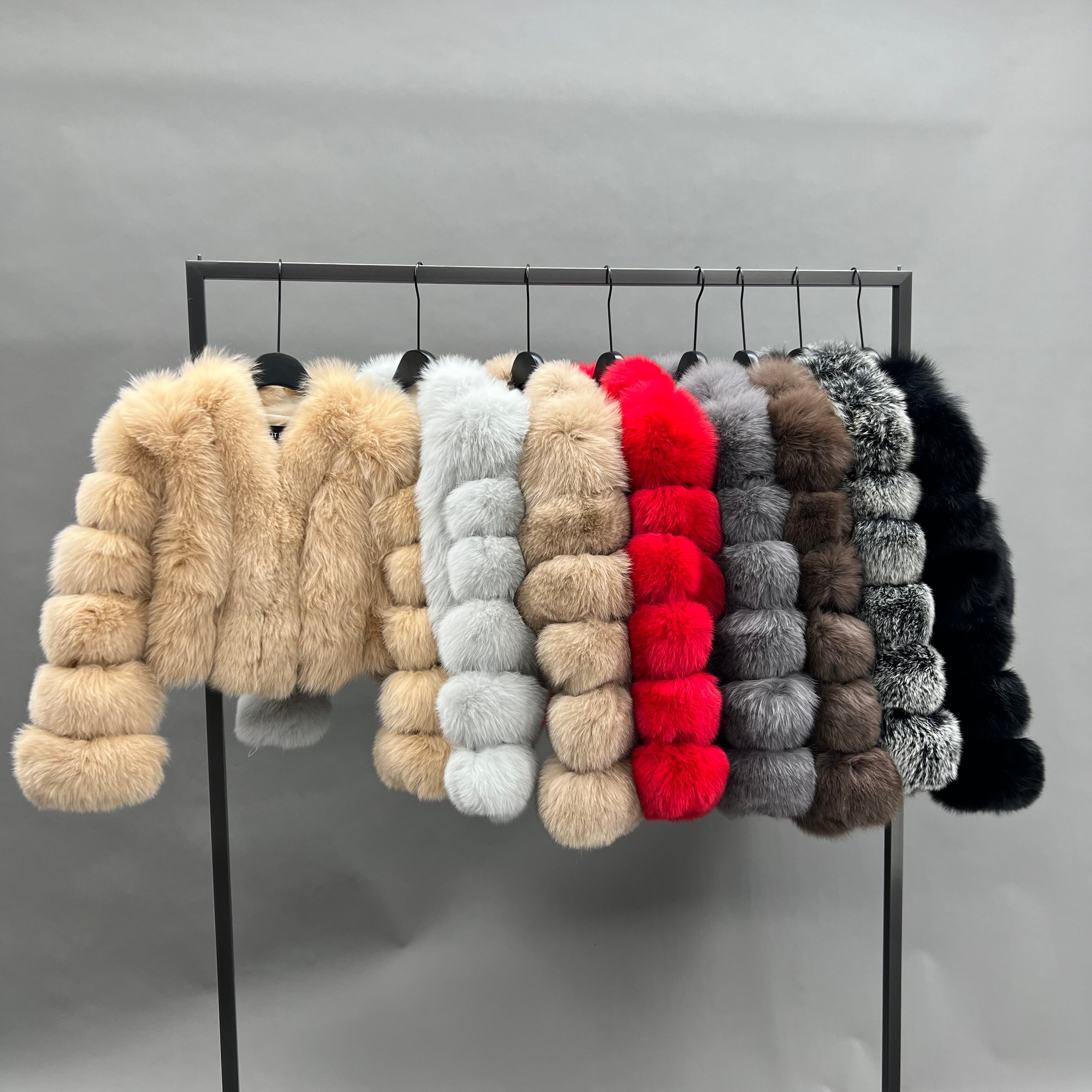 V-neck vertical stripe ultra-short fox fur jackets in multiple colors including champagne, white, red, gray, brown and black displayed on hangers